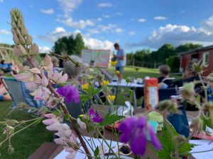 Møte ute på Fossheim med blomster i forgrunnen