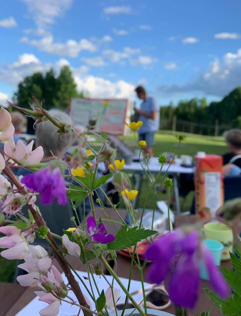 Møte ute på Fossheim med blomster i forgrunnen